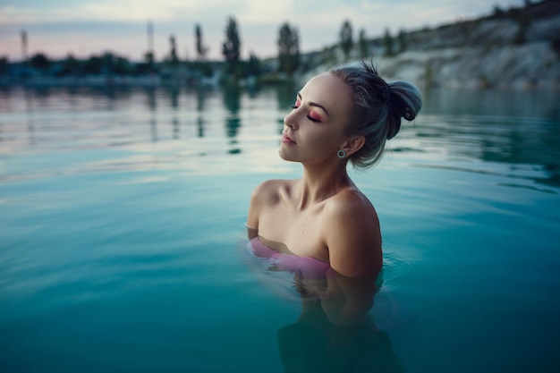 Beautiful and young woman at sunset in the lake. evening rest after a hard day. Milky blue lake water and beautiful sunset