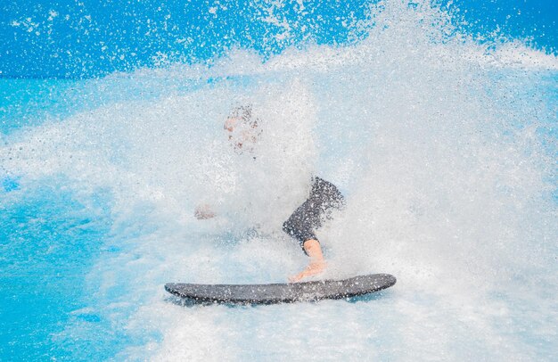 Beautiful young woman surfing on a wave simulator at a water amusement park