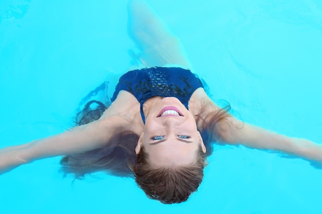 Beautiful young woman swimming in pool