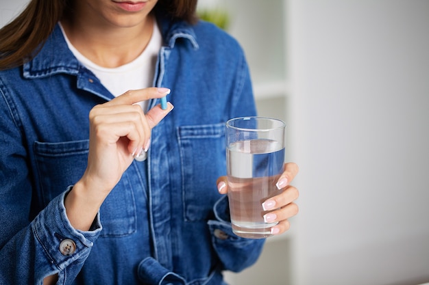 Beautiful young woman taking pill at office.