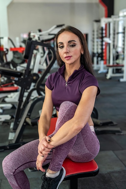 Beautiful young woman trainer with beautiful press on her\
stomach and strong hands trains in the gym. woman tracksuit\
concept