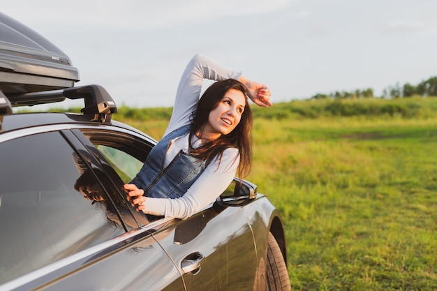 美しい若い女性は、窓から身を乗り出して楽しんで車で旅行します