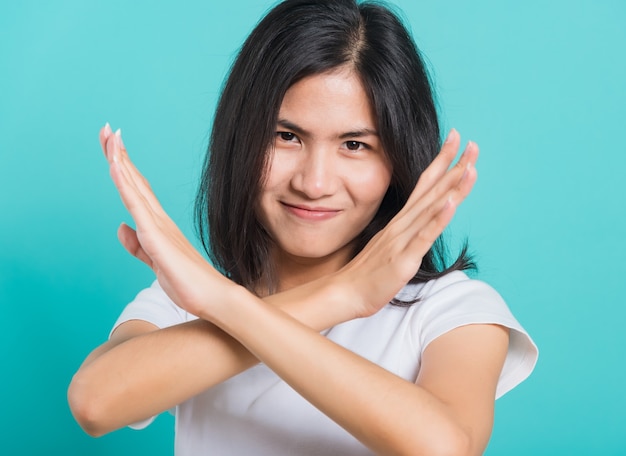 Beautiful young woman unhappy or confident holding two crossing arms say no X sign