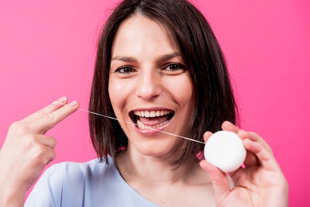 Photo beautiful young woman use dental floss on pink background