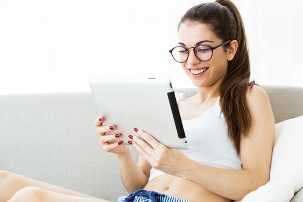 Foto bella giovane donna che utilizza la sua compressa digitale a casa.