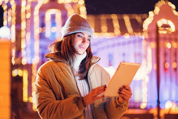 Beautiful young woman using her digital tablet in the winter