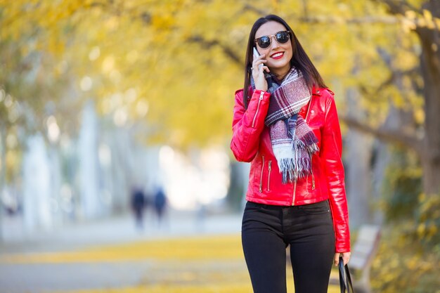 Foto bella giovane donna che utilizza il suo telefono cellulare in autunno.