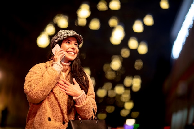 Photo beautiful young woman using her mobile phone in the street at christmas time