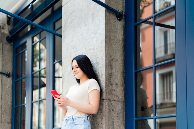 通りで彼女の携帯電話を使用して美しい若い女性。