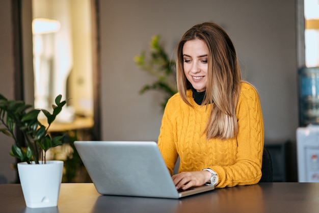 Beautiful young woman using laptop indoors.