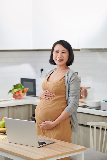 부엌에서 노트북을 사용 하여 아름 다운 젊은 여자