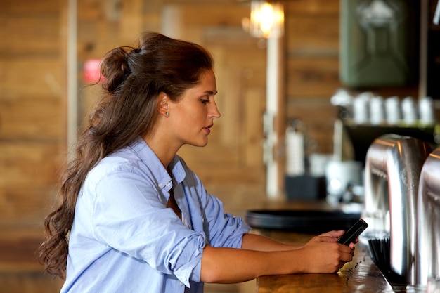 Foto bella giovane donna con cellulare al bar