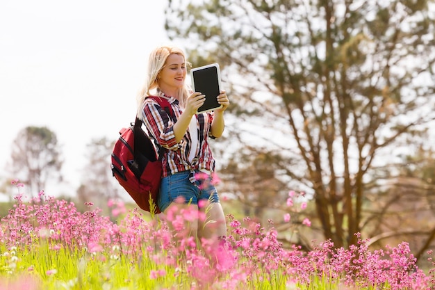 야외 산 배경에서 태블릿 컴퓨터를 사용하는 아름다운 젊은 여성.