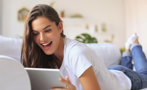 Beautiful young woman using tablet sitting on sofa at home at living room