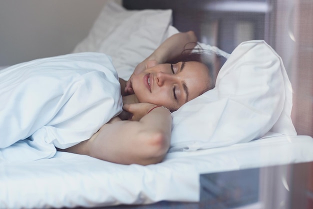 Beautiful young woman wakes up in her bed fully rested A woman with a gentle smile in bed after waking up