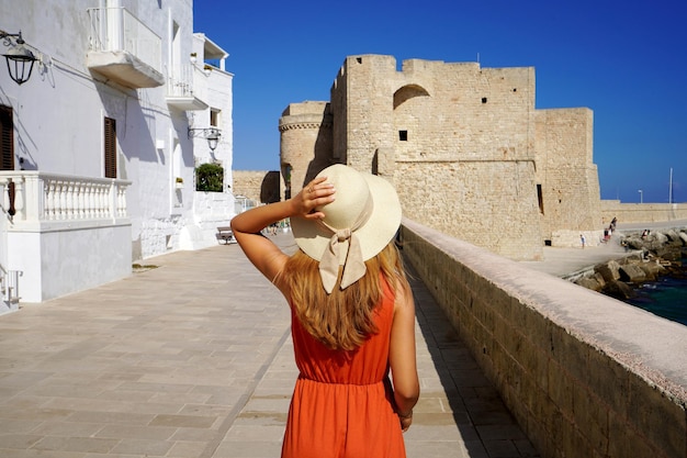 Beautiful young woman walking towards Monopoli castle in Apulia Italy