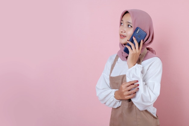 Beautiful young woman wearing apron with mobile phone smile and happy