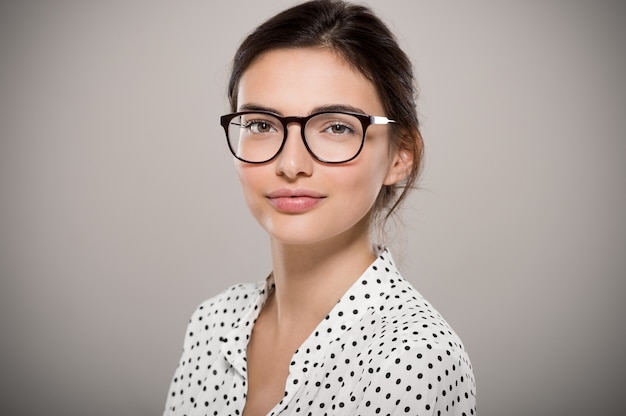 Foto bella giovane donna che indossa occhiali da vista isolati su grigio