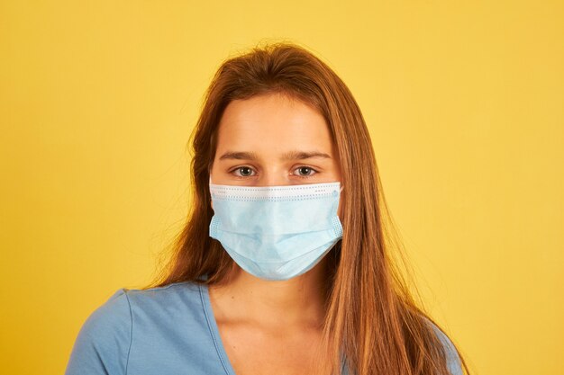 コロナウイルス感染を防ぐためにフェイスマスクを身に着けている美しい若い女性
