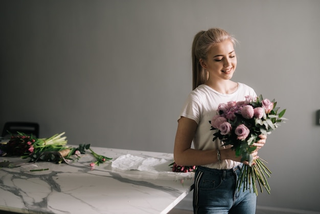 花の花束を保持しているファッションの服を着て美しい若い女性