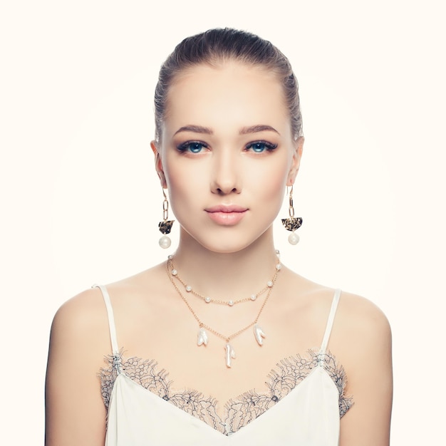 Beautiful young woman wearing fashion golden chain earrings and necklace with white pearls portrait