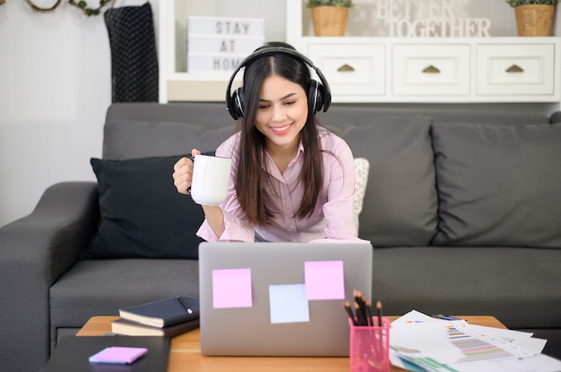 A beautiful young woman wearing headset is making video\
conference call via computer at home , business technology concept\
.