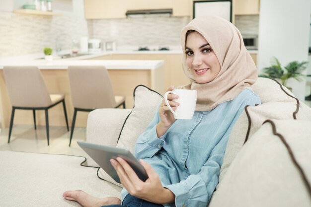 Beautiful young woman wearing hijab drinking a cup of tea while