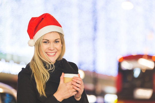 Beautiful young woman wearing Santa hat in London
