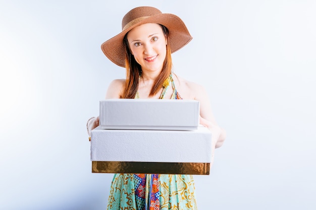 Beautiful young woman wearing summer dress, hat on white background with copy space showing white boxes. internet summer shopping concept