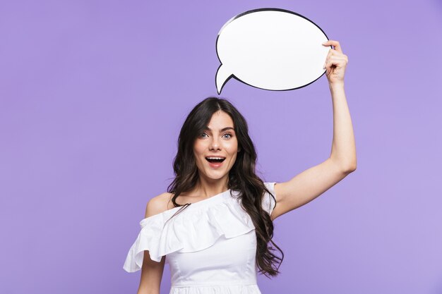 Beautiful young woman wearing summer outfit standing isolated over violet wall, showing blank speech bubble