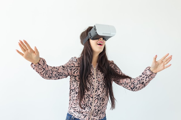 Beautiful young woman wearing virtual reality glasses and playing a game while standing against a