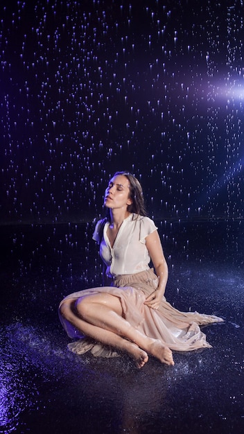 Photo beautiful young woman in a wet dress in the rain shooting in the studio on a black background