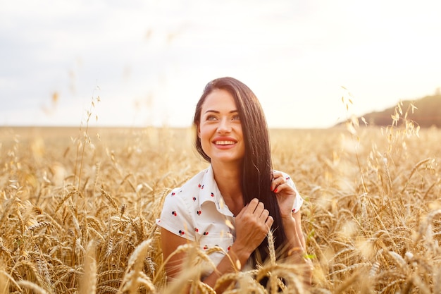 Beautiful young woman in wheat field cute brunette girl of caucasian appearance in casual clothes is...