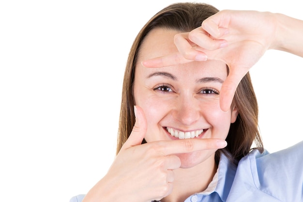 Foto bella giovane donna su sfondo bianco isolato sorridente facendo cornice con le mani e le dita con la faccia felice nel concetto di creatività e fotografia