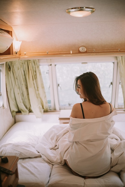 Bella giovane donna in una camicia bianca nella camera da letto a casa