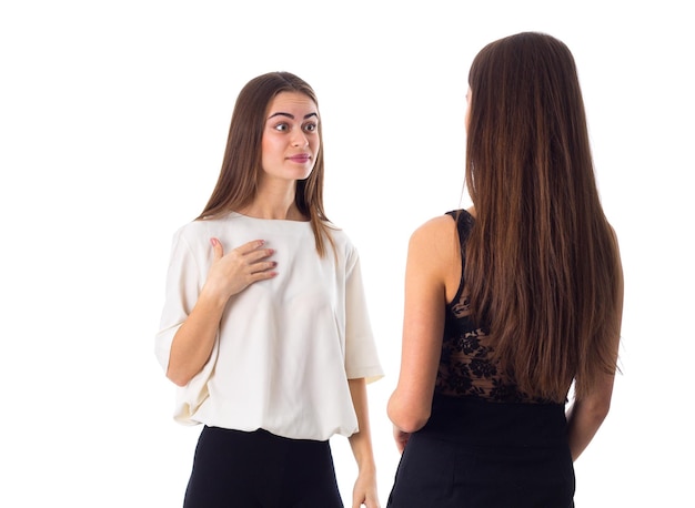 Bella giovane donna in camicia bianca che parla con un altro su sfondo bianco in studio