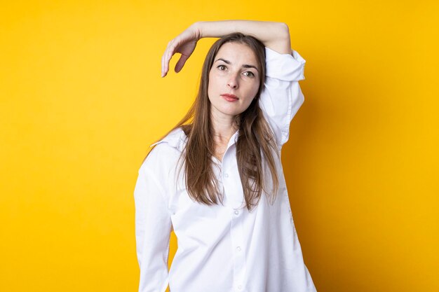 Beautiful young woman in a white shirt on a yellow background