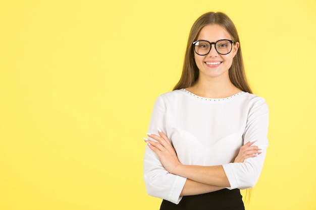 Beautiful young woman in a white shirt on a yellow background