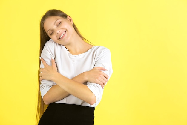 Bella giovane donna in una camicia bianca su sfondo giallo