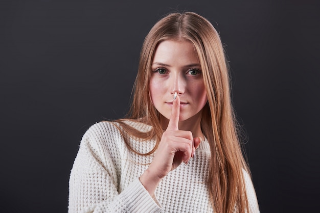 beautiful young woman in white sweater and jeans isolated on black background