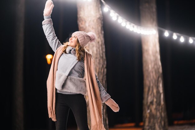 Beautiful young woman in winter time Happy winter time in forest Festive garland lights Christmas