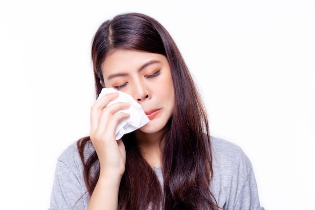 美しい若い女性が灰色の背景にティッシュペーパーで目を拭いています