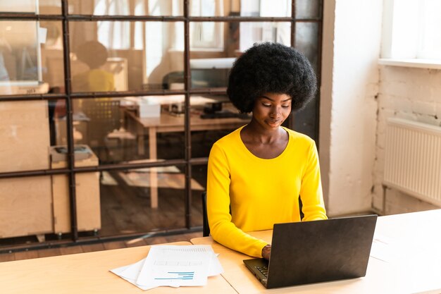 Beautiful young woman with the afro haircut working in the office