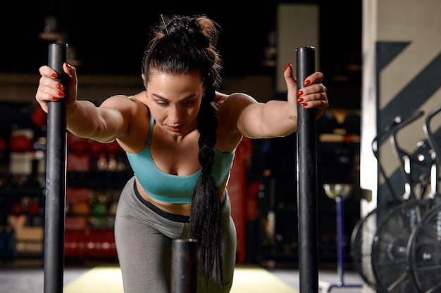 Beautiful young woman with barbell weight plate working out in sports club