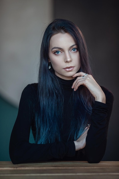 Beautiful young woman with black and blue hair and a black turtleneck posing in a stylish room Fashion studio shot Retro fashion