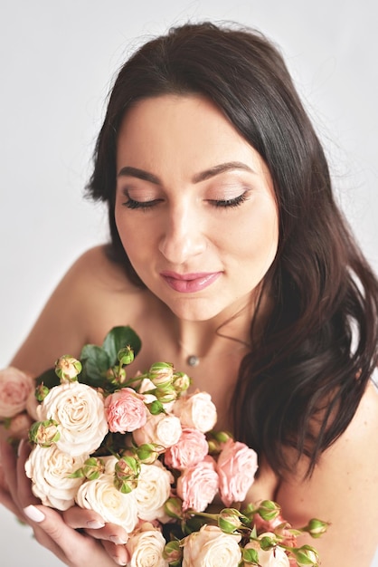 Beautiful young woman with bouquet flowers of roses International Women's Day