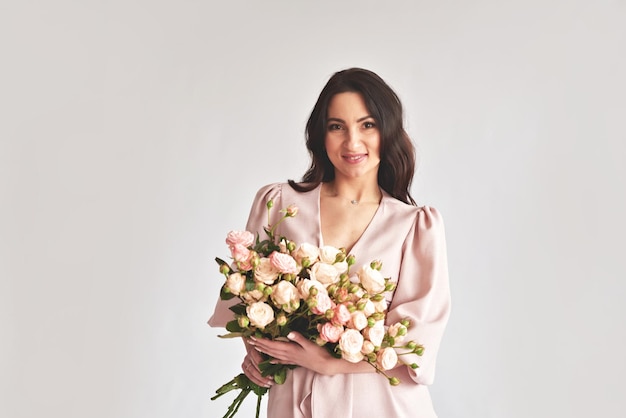 Beautiful young woman with bouquet flowers of roses International Women's Day