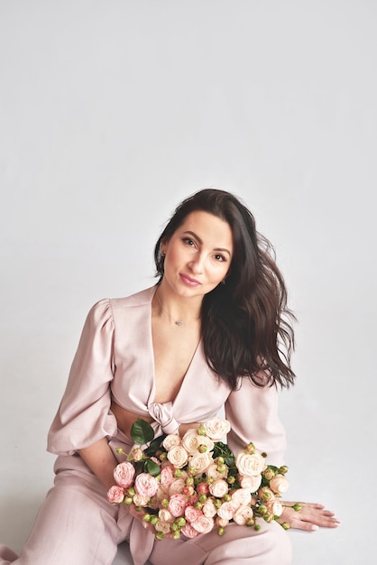 Beautiful young woman with bouquet flowers of roses International Women's Day