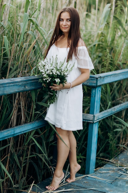 Foto bella giovane donna con un mazzo di fiori di campo con il trucco all'aperto