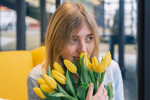 黄色いチューリップの花束を持つ美しい若い女性